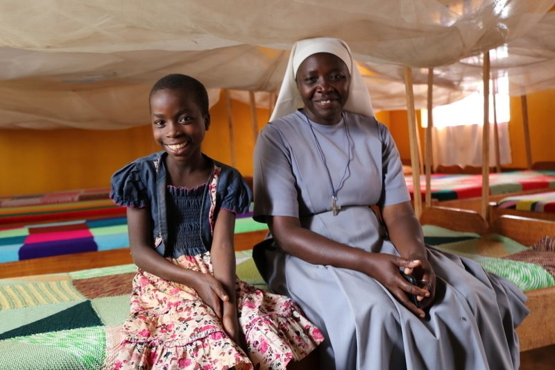 Alice Sits On Her Bed With Orphanage Manager, Sister Godeberthe